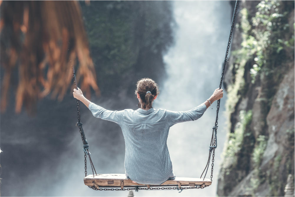 woman sitting on a swing overlooking a waterfall