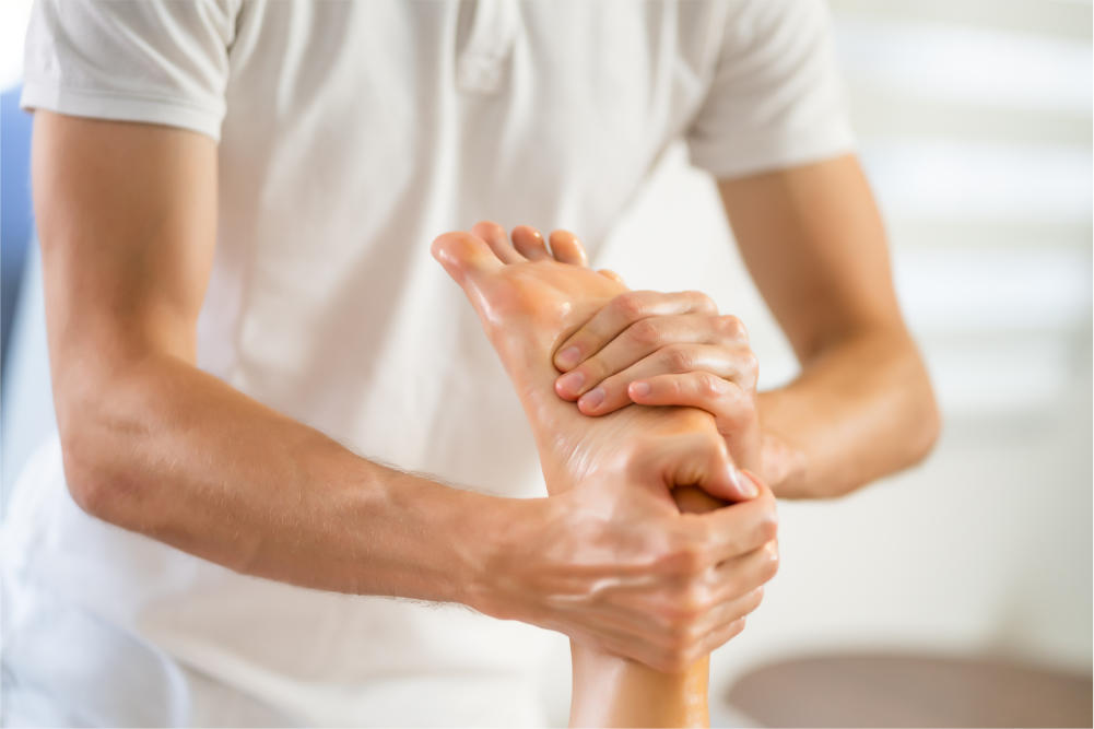 female foot is being massaged by a reflexologist in a white setting
